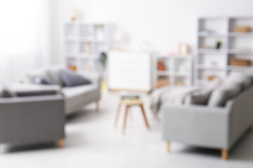 Armchair, soft sofas and coffee table in interior of living room. Blurred view