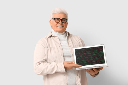 Senior programmer with laptop on light background