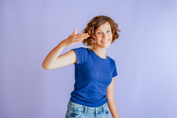 Joyful little girl showing greeting with welcoming gesture and happy vibe for welcome on vibrant blue studio background with cheerful energy