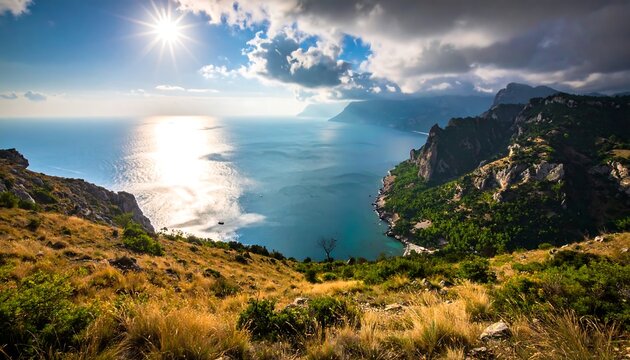 Overlooking a vast body of water reflecting the sun's brilliance. Rugged cliffs and vibrant vegetation frame the expansive view