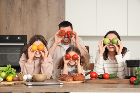 Happy family with fresh food at table in kitchen