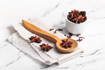 Wooden spoon and bowl with anise stars on white background