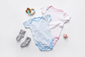 Baby clothes with pacifier and rattle on white background