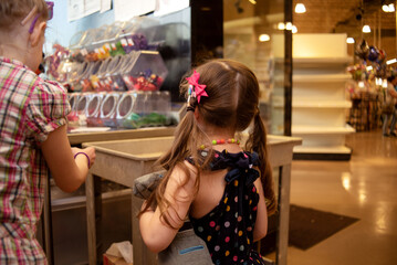 Child with pigtails shopping at the balloon counter in a grocery store market