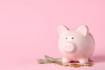 Piggy bank with dollar banknotes and coins on pink background
