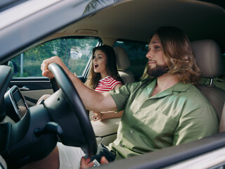 A candid interior shot featuring a couple in a car, with the female passenger shouting and the male driver focused on the road, capturing a tense moment.