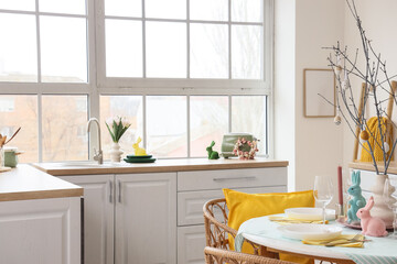 Interior of light kitchen decorated for Easter with dining table and counters