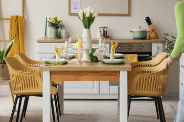 Woman pushing chair away from dining table in kitchen decorated for Easter
