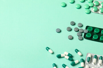 Different pills in blister packs on green background, closeup