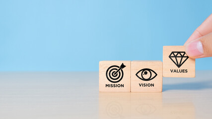 Mission, vision and values of company. Purpose business concept. Hand holds wooden cube with mission symbol and vision, values symbols on blue background. Modern flat design. Business presentation