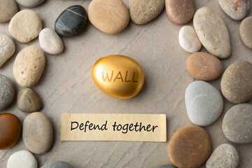 Gold egg within a stone circle saying Wall defend together