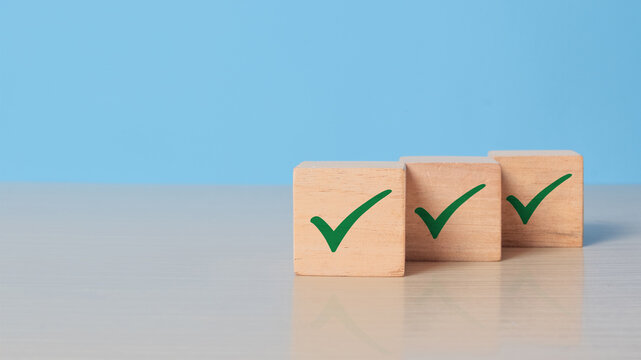 Checklist concept. Green correct sign and tick check mark to wooden cube block with copy space. Quality and ISO symbol. Wooden cube with green checkmark icon.