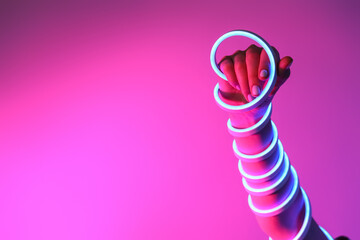 Toned female hand with neon tape on pink background
