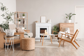 Cozy interior of living room with fireplace, armchairs, sofa and table