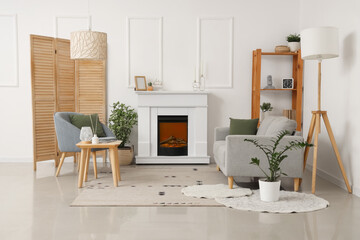 Fireplace, sofa and houseplants in interior of light living room