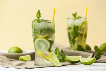 Glasses of fresh Mojito cocktail with limes and mint on white table
