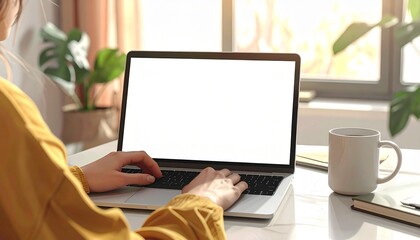 Closeup over the shoulder view of a person working on a modern laptop with a blank white display for mockup purposes. The scene include warm ambient lighting. Minimalist desk setup. High quality image