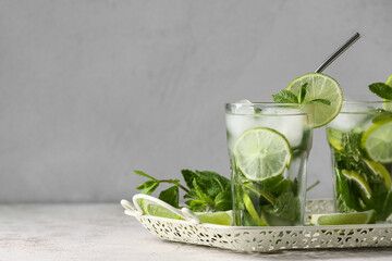 Tray with glasses of tasty mojito and ingredients on grey grunge background, closeup