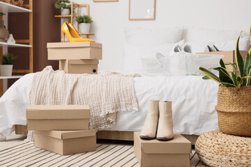 Stylish boots with shoe boxes in bedroom