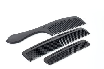 A set of three black plastic combs for hairstyling and grooming, isolated on a white background.