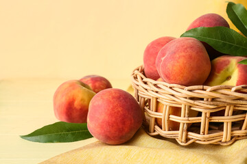 Wicker basket of fresh peaches on beige background