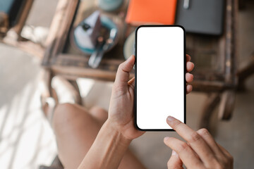 Close-up of hands holding a smartphone with a blank screen, perfect for app or website mockup in a cozy indoor setting.
