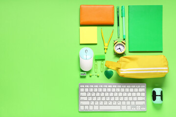 Composition with modern keyboard, mouse and school supplies on green background