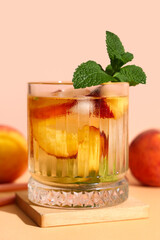 Glass of fresh peach lemonade with mint on orange table against beige background
