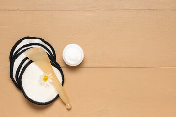 Composition with spatula and reusable cotton pads on beige  wooden background, closeup