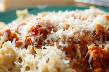 A closeup view of a plate of gluten-free mafalde pasta, topped with dairy-free parmesan cheese.