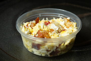 A view of a plastic container of instant breakfast bowl, in a microwave setting.