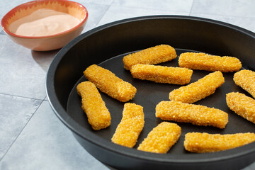 A view of a round baking sheet of gluten-free fish sticks.