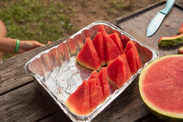 Tray of half-eaten watermelon slices on picnic table at summer family cookout