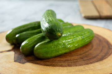 A view of pile of Persian cucumbers, on a wood board.