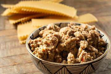 A view of a bowl of Italian sausage, next to some lasagna pasta sheets.