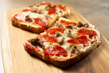 A closeup view of an open face gluten-free, dairy-free pizza sandwich, on a wood board.
