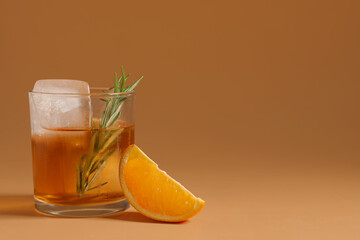 Glass of tasty Old Fashioned cocktail with rosemary on brown background