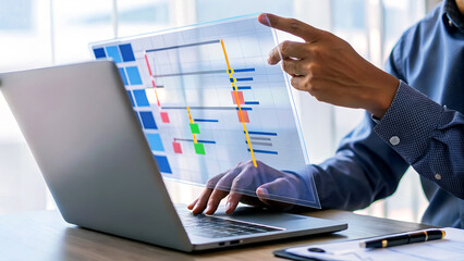Dynamic professional analyzing project timeline Gantt chart on transparent screen alongside modern laptop, driving business success.