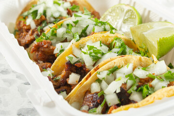 A closeup view of a container al pastor tacos.