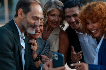Business team sharing a funny moment while watching a smartphone outdoors
