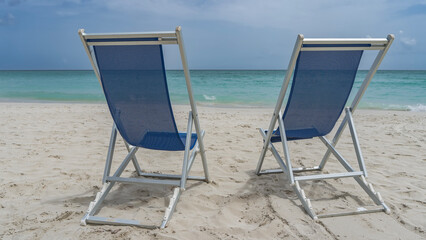 Two deck chairs with mesh seats on the sandy beach. White sand, calm turquoise ocean, blue sky. Summer holidays. Cuba. Varadero. Resort. Hotel.