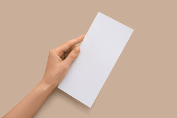 Female hand with blank card on beige background