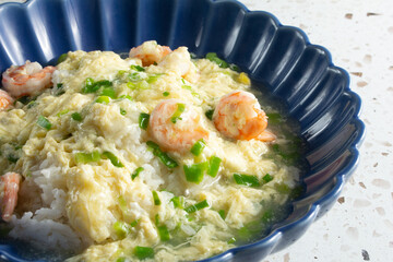 A view of a rice dish, topped with egg and shrimp.
