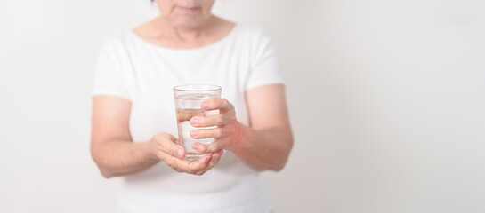 Elderly woman having Tremor hand during hold water glass. Parkinson disease April awareness month, Carpal Tunnel Syndrome, rheumatoid and brain injury, Neurological disorder and Senior health concept