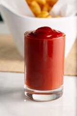 A view of ketchup presented in a small shot glass.