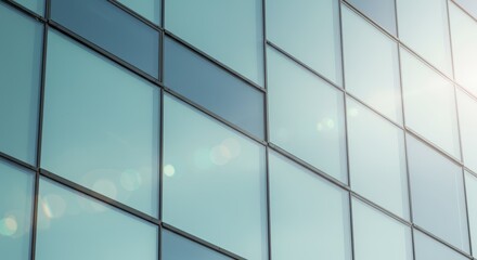 Modern architectural glass facade featuring a grid of reflective windows reflecting sunlight and sky creating a pattern