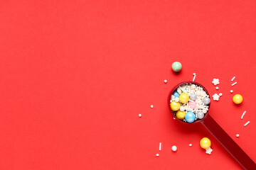 Measuring spoon with sprinkles on red background