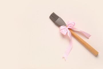 Pastry brush with bow on beige background