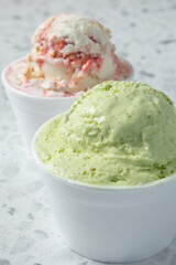 A view of a scoop of pistachio ice cream, and strawberry cheesecake ice cream.