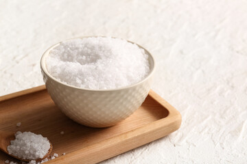 Wooden board with bowl and spoon of sea salt on grunge background